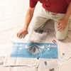 Mark Powers sprays repositionable mounting adhesive onto the back of the stencil