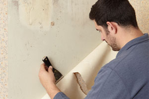 Sal Vaglica stripping wallpaper with a putty knife