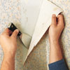 peeling back wallpaper using a metal putty knife 