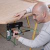 man using nail gun to construct poker table