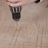 man drilling pilot holes on poker table