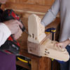 man drilling pilot holes in feet of poker table