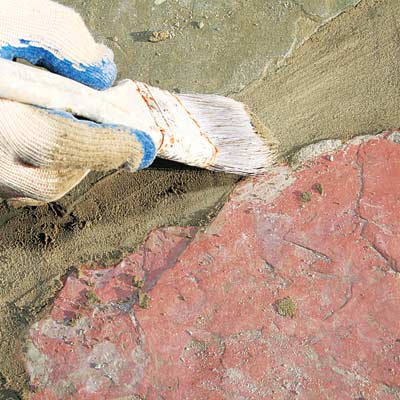brushing away excess mortar from a stone walkway with a paintbrush