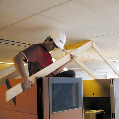 Mark Powers assembles a roof frame over an office cubicle