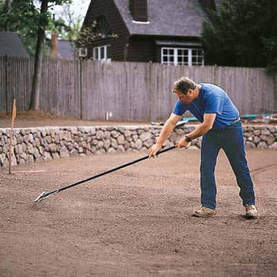 Roger Cook rakes the soil to level the surface