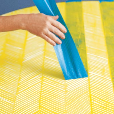 removing the last row of tape for the finished herringbone pattern on a tabletop