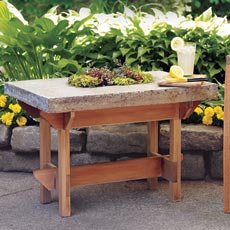 a hypertufa table next to a deck chair on a patio