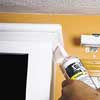 applying caulk to seams in primed cabinets