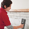 photo of thinset being trowelled onto brick fireplace surround