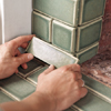 photo of cut tile being set at bottom of fireplace surround