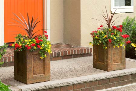 two concrete planters with colorful flowers on the entryway of a house to illustrate How to Make a Concrete Planter for this old house