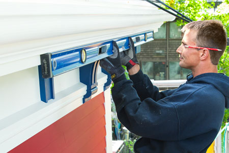 installer Peter Robinson makes sure the gutter slopes during installation of fiberglass gutters
