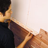 Photo of man attaching glued board to the wall, interlocking with the groove of the board below it.