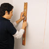 Image of person holding a level to the wall to mark the line of studs, once found with the stud finder.