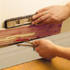 Image of hands using a compass and level to mark the gap between the baseboard and the first row of cedar in order to create a level first course.