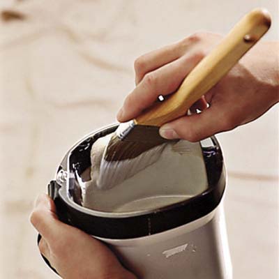 man dipping brush into the bucket of paint