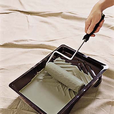 man rolling paintbrush in the paint tray