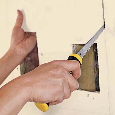 Cutting along pencil lines, using keyhole saw.
