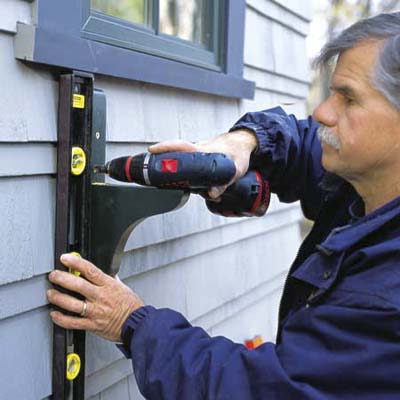 checking for plumb before installing the second screw of a window box bracket